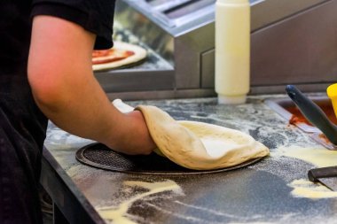 Aşçı mutfakta, pizzanın malzemelerini koyuyor. Pizza konsepti. Gıda üretimi ve teslimatı.