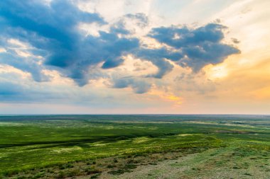 Bozkırda bulutların olduğu manzaralı günbatımı.