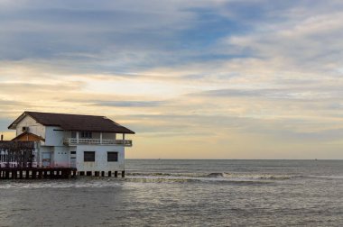 Tayland, Khlong Yai 'de gün doğumunda deniz kenarındaki ayaklıklarda bir ev.