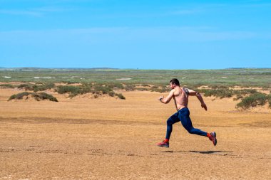 Rusya, Baskunchak, 25 Mayıs 2019, spor koşucusu, spor koşucusu, çölde üstsüz koşuyor. Hızlı koşu sırasında kızgın güneşin altında çok hızlı koşan formda bir sporcu..