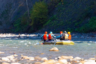 Bir grup genç dağ nehrinde rafting yapıyor..