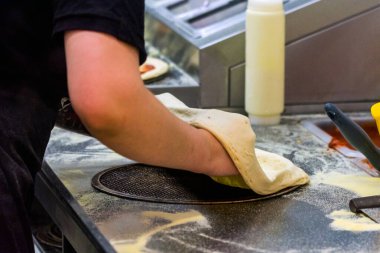 Aşçı mutfakta, pizzanın malzemelerini koyuyor. Pizza konsepti. Gıda üretimi ve teslimatı.