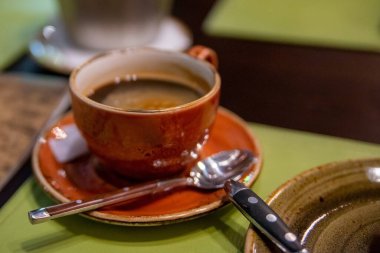 Kahverengi fincanda çay tabağı ve kaşık.