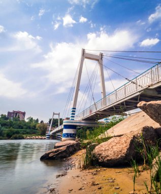 Mavi gökyüzünün altında bulutlu, kablo destekli asma köprü.