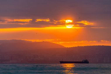 Kargo gemisi altın bir gün batımında ya da gün doğumunda denize açılacak. Güneş batarken ya da doğarken okyanus sevkiyatı. Doğadaki uyum ve güzellik. Huzurlu deniz manzarası.