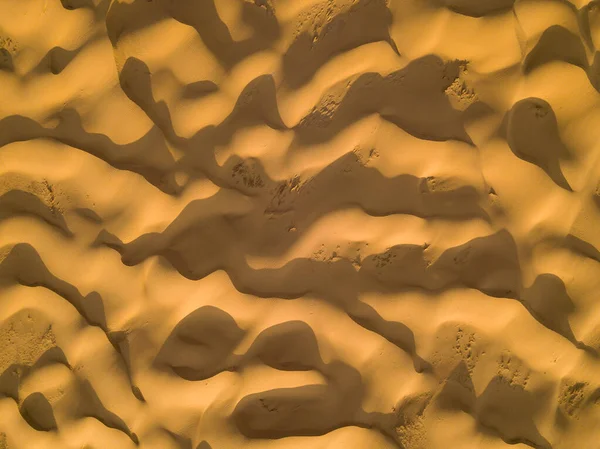 Aerial top view on sand dunes with waves in desert.