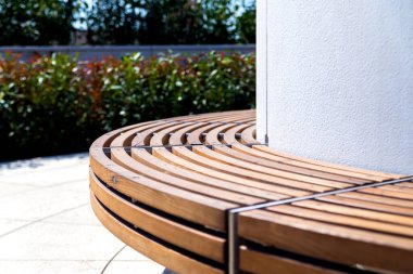 Modern kavisli kahverengi ahşap tasarım tezgahı parktaki yeşil bölgede.