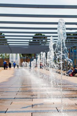 Detaylı olarak parktaki bir fıskiyenin yüksek panjur hızındaki görüntüsü suyun hareketini dondurur ve çeşitli şekillerde asılı damlacıklar, kristal ya da buzla izole edilmiş güzel bir bokeh gibi..