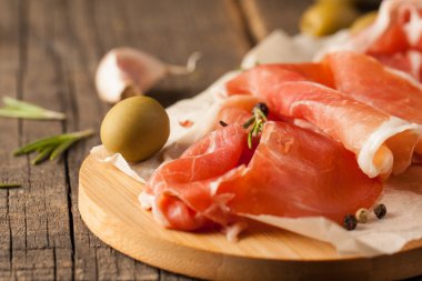 prosciutto ile karışık zeytin ve ahşap kesme tahtası üzerinde kırmızı biber ince dilim closeup