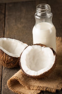 Olgun yarı ahşap bir arka plan üzerine Hindistan cevizi kesti. Olgun yarı ahşap bir arka plan üzerine Hindistan cevizi sütü ile kesmek