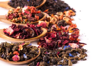 Ahşap rustik zemin üzerine tahta kaşık kuru çay. Kırmızı, yeşil ve siyah çay yaprakları. Makro fotoğraf. Rustik tarzı ve kavram.