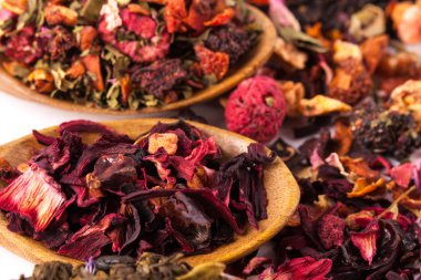 Ahşap rustik zemin üzerine tahta kaşık kuru çay. Kırmızı, yeşil ve siyah çay yaprakları. Makro fotoğraf. Rustik tarzı ve kavram.