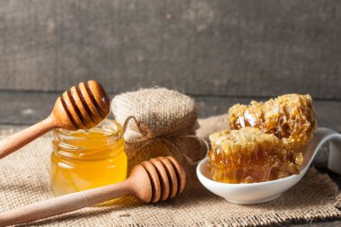 Tatlım gelen ahşap bal ayı gri rustik ahşap arka plan üzerinde bir kavanoza damlama