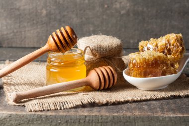 Tatlım gelen ahşap bal ayı gri rustik ahşap arka plan üzerinde bir kavanoza damlama