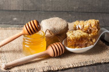 Tatlım gelen ahşap bal ayı gri rustik ahşap arka plan üzerinde bir kavanoza damlama