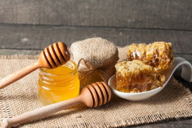 Tatlım gelen ahşap bal ayı gri rustik ahşap arka plan üzerinde bir kavanoza damlama