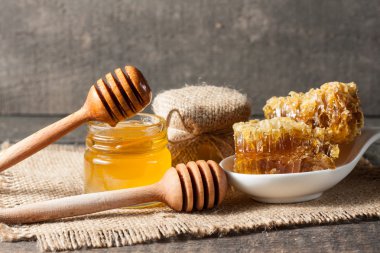 Tatlım gelen ahşap bal ayı gri rustik ahşap arka plan üzerinde bir kavanoza damlama