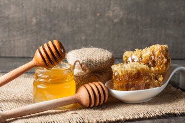 Tatlım gelen ahşap bal ayı gri rustik ahşap arka plan üzerinde bir kavanoza damlama