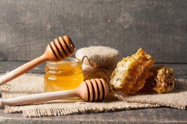 Tatlım gelen ahşap bal ayı gri rustik ahşap arka plan üzerinde bir kavanoza damlama