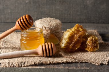 Tatlım gelen ahşap bal ayı gri rustik ahşap arka plan üzerinde bir kavanoza damlama