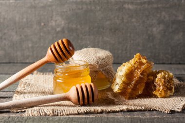 Tatlım gelen ahşap bal ayı gri rustik ahşap arka plan üzerinde bir kavanoza damlama