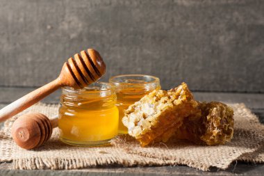 Tatlım gelen ahşap bal ayı gri rustik ahşap arka plan üzerinde bir kavanoza damlama