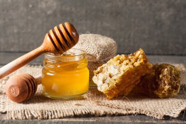 Tatlım gelen ahşap bal ayı gri rustik ahşap arka plan üzerinde bir kavanoza damlama