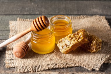 Tatlım gelen ahşap bal ayı gri rustik ahşap arka plan üzerinde bir kavanoza damlama