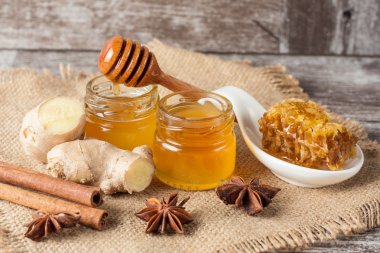 Tatlım gelen ahşap bal ayı gri rustik ahşap arka plan üzerinde bir kavanoza damlama