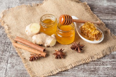 Tatlım gelen ahşap bal ayı gri rustik ahşap arka plan üzerinde bir kavanoza damlama