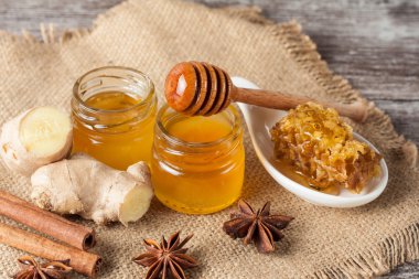 Tatlım gelen ahşap bal ayı gri rustik ahşap arka plan üzerinde bir kavanoza damlama