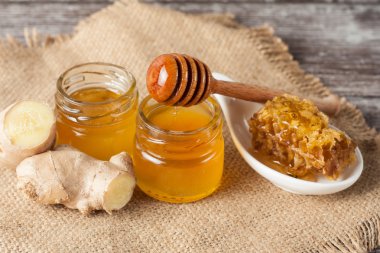 Tatlım gelen ahşap bal ayı gri rustik ahşap arka plan üzerinde bir kavanoza damlama