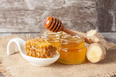 Tatlım gelen ahşap bal ayı gri rustik ahşap arka plan üzerinde bir kavanoza damlama