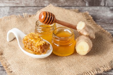 Tatlım gelen ahşap bal ayı gri rustik ahşap arka plan üzerinde bir kavanoza damlama