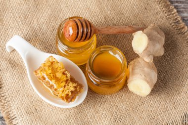 Tatlım gelen ahşap bal ayı gri rustik ahşap arka plan üzerinde bir kavanoza damlama