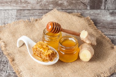 Tatlım gelen ahşap bal ayı gri rustik ahşap arka plan üzerinde bir kavanoza damlama