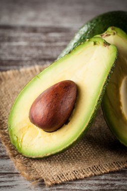 Ahşap masa üzerinde bir avokado ve avokado yağı close-up. Sağlıklı gıda kavramı.