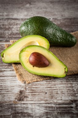 Ahşap masa üzerinde bir avokado ve avokado yağı close-up. Sağlıklı gıda kavramı.