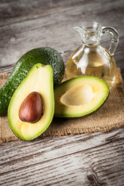 Ahşap masa üzerinde bir avokado ve avokado yağı close-up. Sağlıklı gıda kavramı.