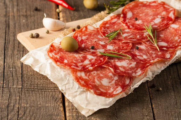 Chorizo sausage and salami, thin cut. spanish salami on the wood background with spices, paprika, pepper. Spicy food. Chili. — Stock Photo, Image