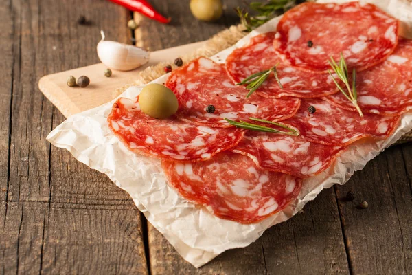 Salchicha de chorizo y salami, corte fino. salami español en el fondo de madera con especias, pimentón, pimienta. Comida picante. Chili.. —  Fotos de Stock