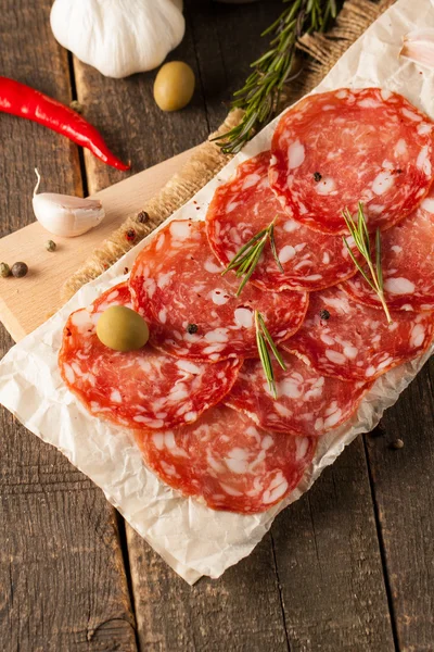 Chorizo worst en salami, dun gesneden. Spaanse salami op houtondergrond met specerijen, paprika, peper. Pittig eten. Chili. — Stockfoto