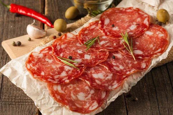 Salchicha de chorizo y salami, corte fino. salami español en el fondo de madera con especias, pimentón, pimienta. Comida picante. Chili.. — Foto de Stock