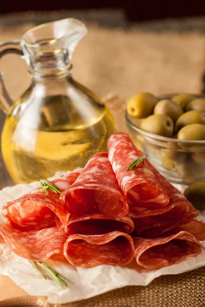 Italiaanse salami met olijven en specerijen op houten achtergrond — Stockfoto