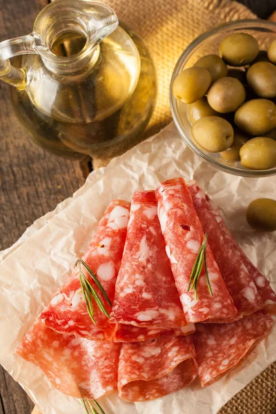 Salame italiano com azeitonas e especiarias em fundo de madeira — Fotografia de Stock