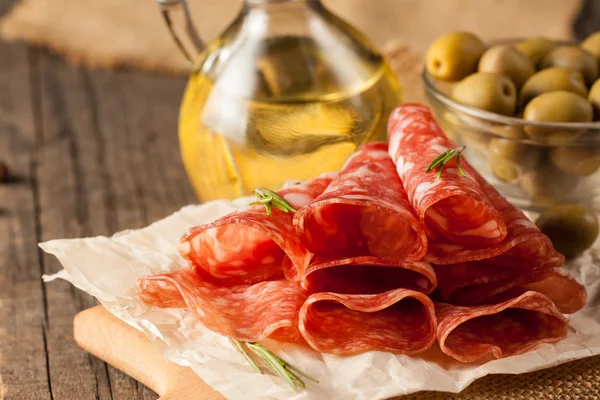 Итальянская салями с оливками и специями на деревянном фоне — стоковое фото