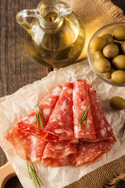 Salami italiano con aceitunas y especias sobre fondo de madera —  Fotos de Stock