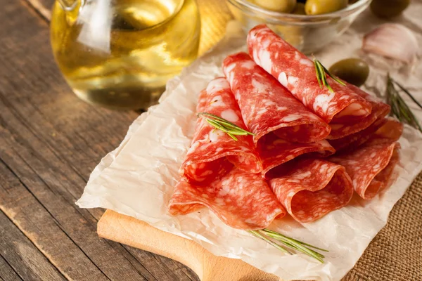 Salami italiano con aceitunas y especias sobre fondo de madera — Foto de Stock