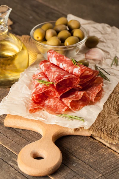 Salami italiano con aceitunas y especias sobre fondo de madera — Foto de Stock