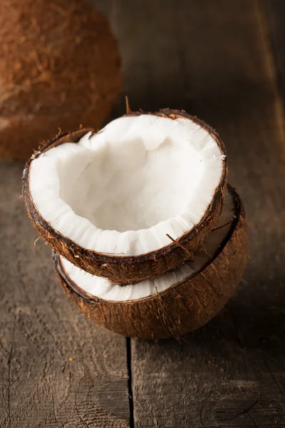 Noix de coco mûre demi coupée sur un fond en bois. Noix de coco demi-coupée mûre avec du lait sur un fond en bois — Photo